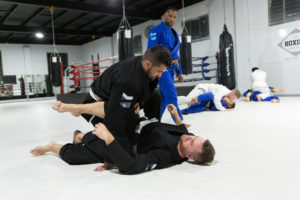 a student passes the guard of another student under the watchful eye of a BJJ coach