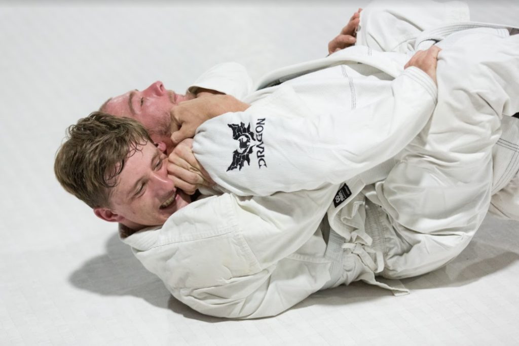 Two men get really close in partner BJJ drills.