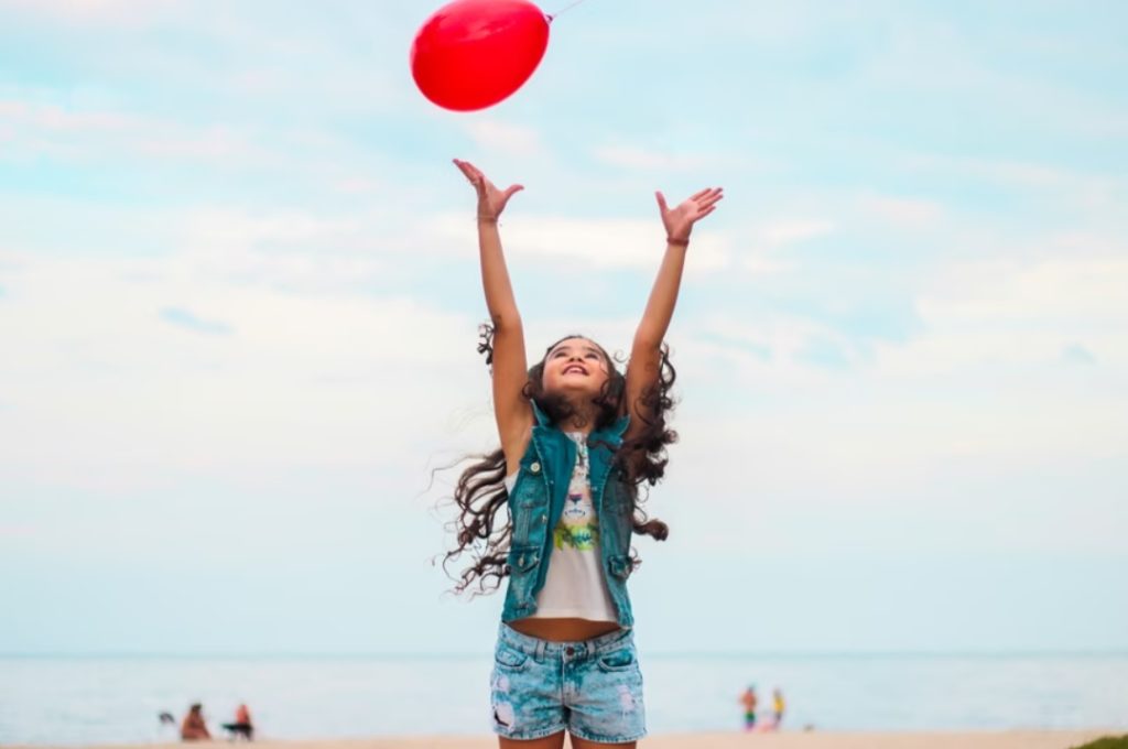 a young girl tosses a balloon