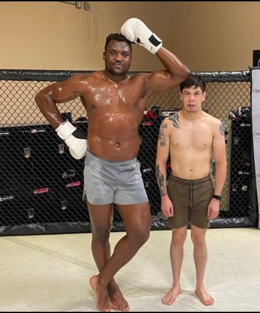 francis ngannou and brandon moreno standing next to each other in the cage