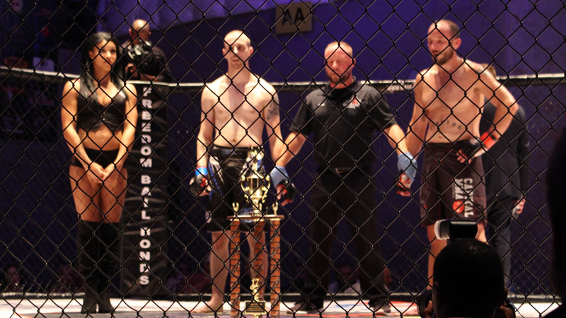 Two MMA athletes in the cage waiting to get their hand raised.