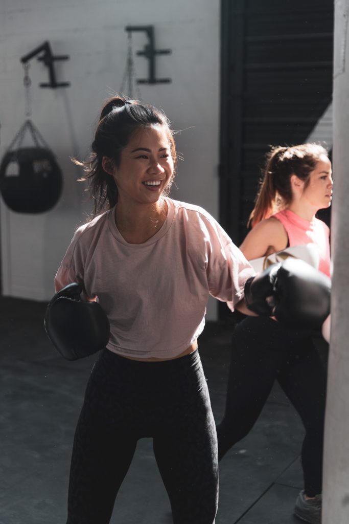 a female smiling while hitting the bag during martial arts classes