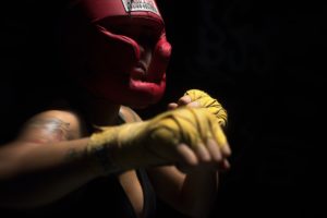 A man wears hand wraps and a head gear, presumably for an amateur boxing match.