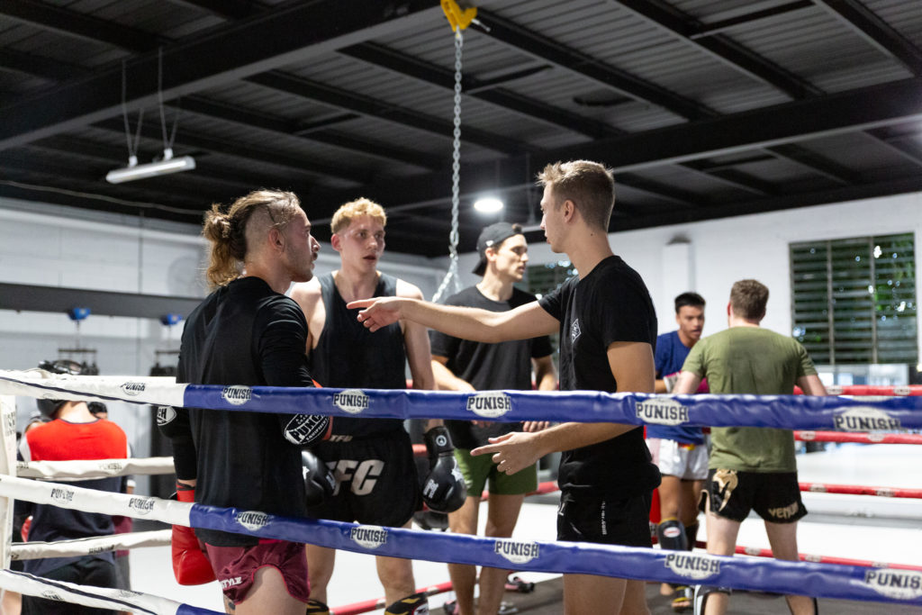A trainer instructs a couple of fighters in the ring
