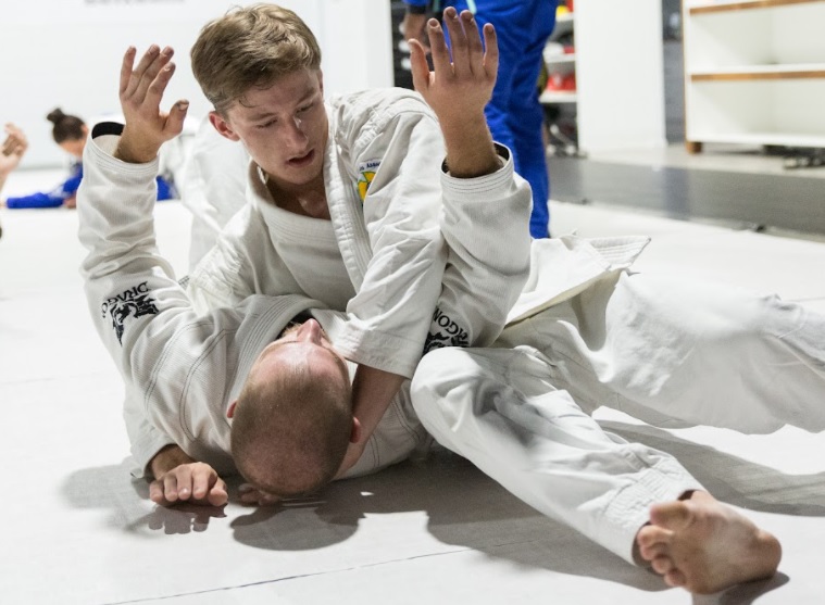 two guys wearing white bjj gi tangle up in a roll